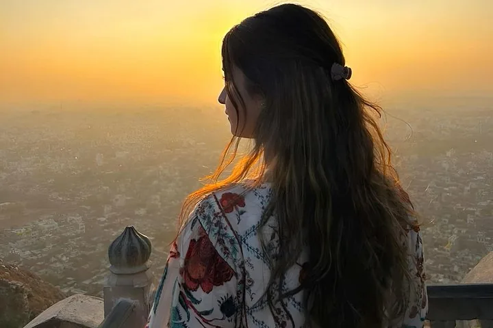 A woman looking out over the city from Nahargarh Fort at sunset.